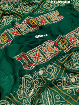 A green bandhej saree with royal aari and real mirror work, displayed on a surface.
