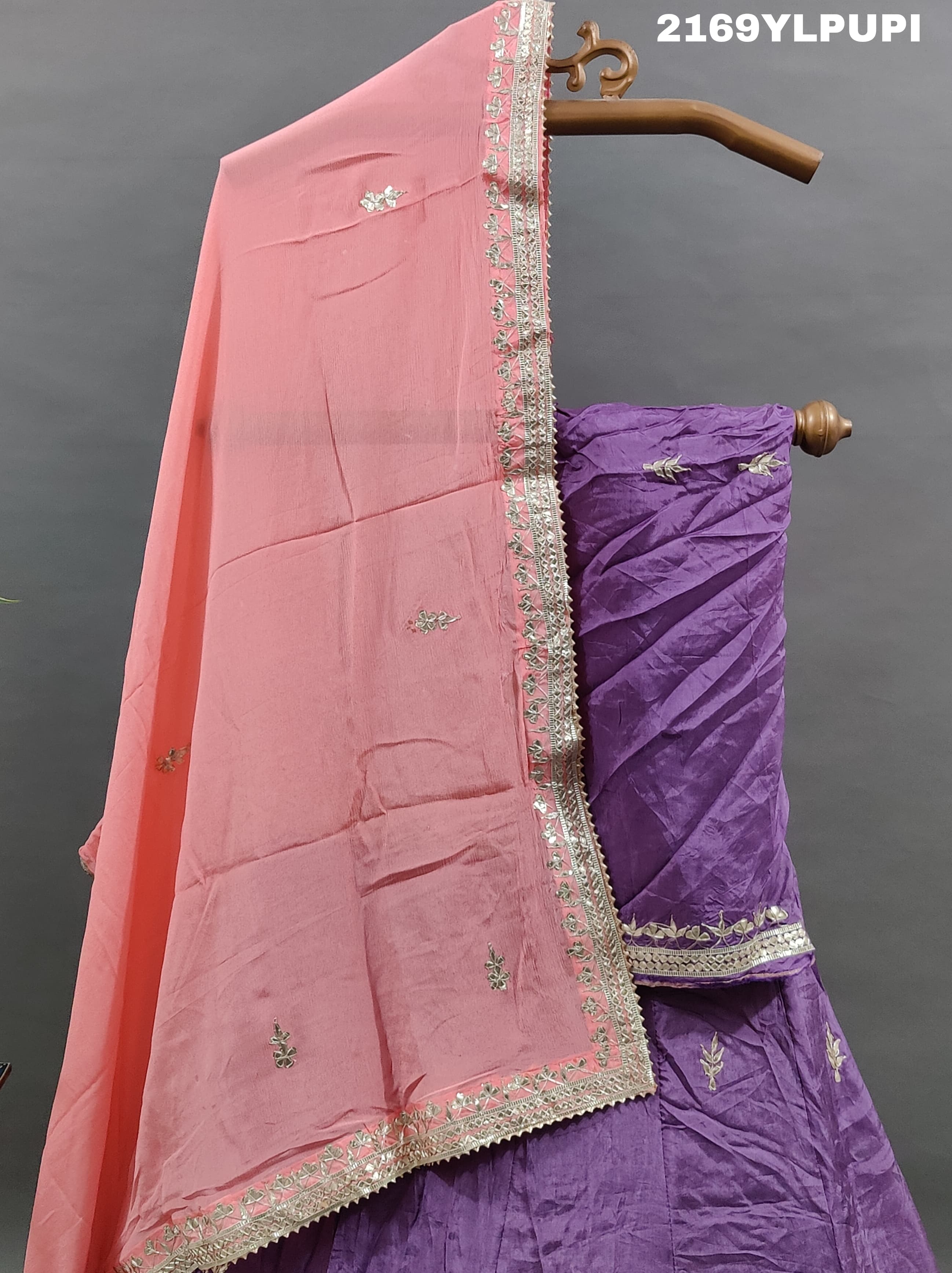 A traditional wear lehenga in purple with detailed embroidery and a pink dupatta.
