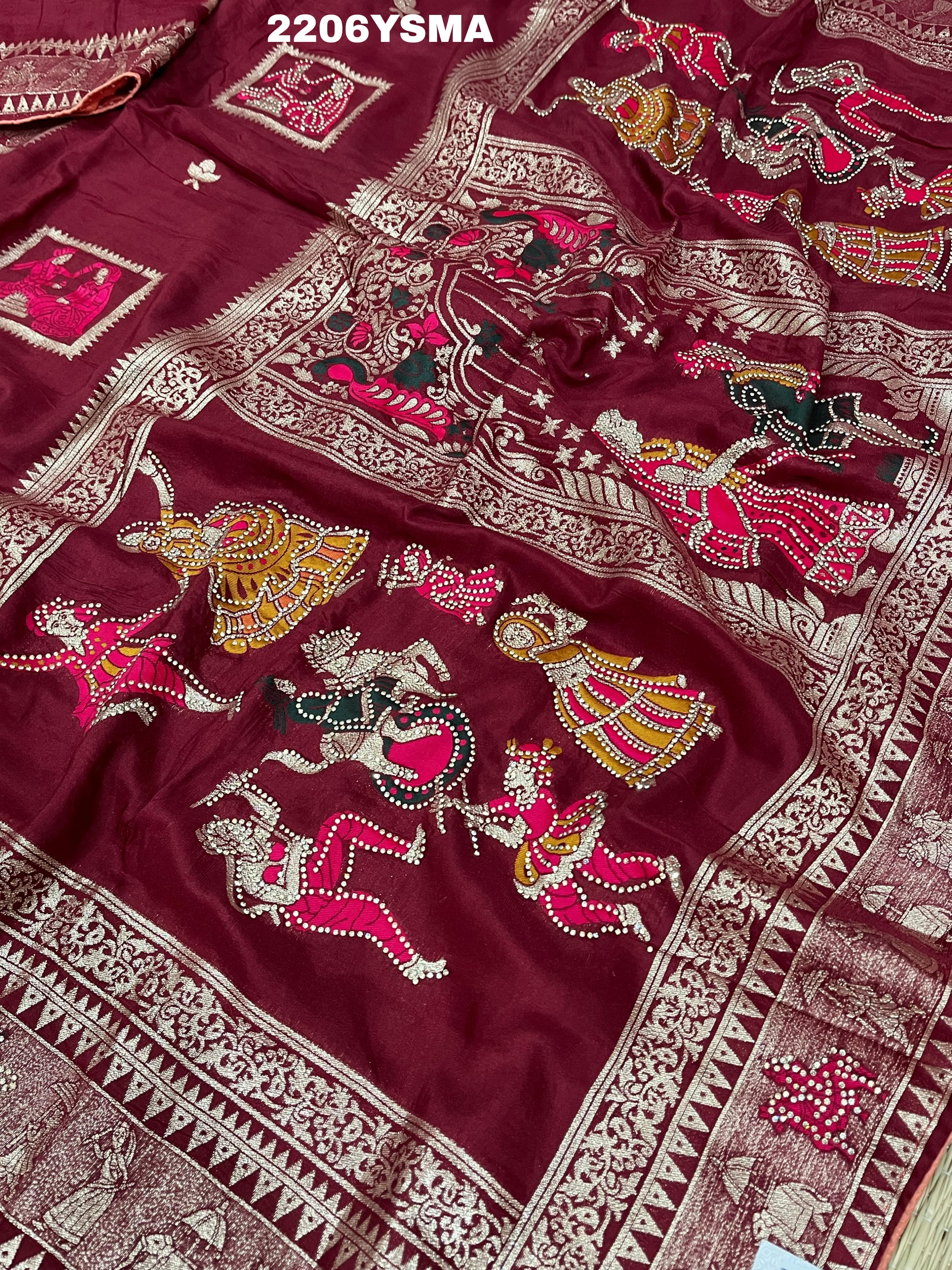 A wine colored Dola Silk saree with Banarasi style stone work, depicting traditional Indian motifs and characters.