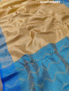 A tissue silk banarasi saree with zari weaving, featuring a blue and gold design on a beige fabric, meant for party or casual wear.