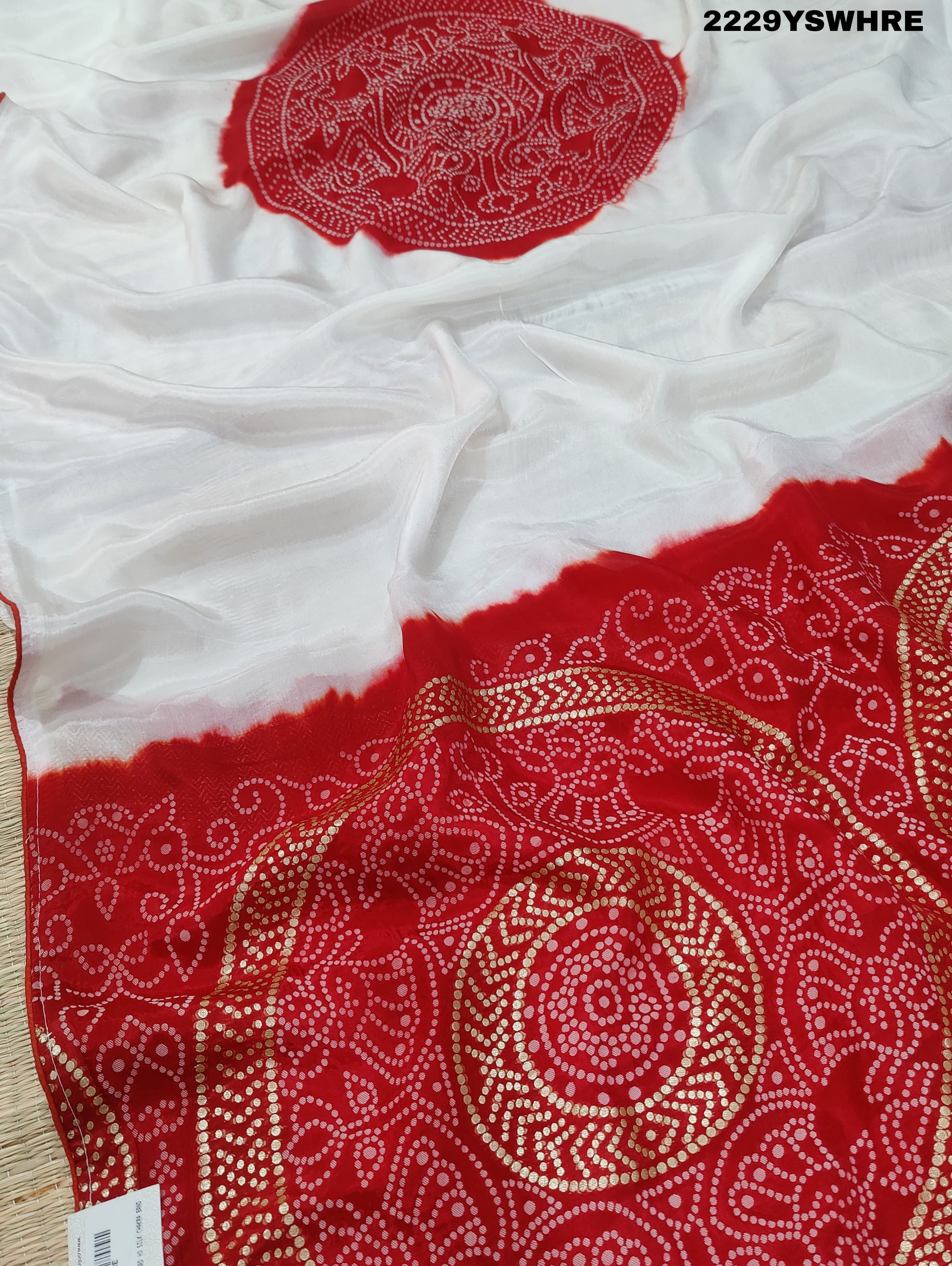 A traditional saree with red and white colors and intricate patterns, predominantly red at one end with a floral design.