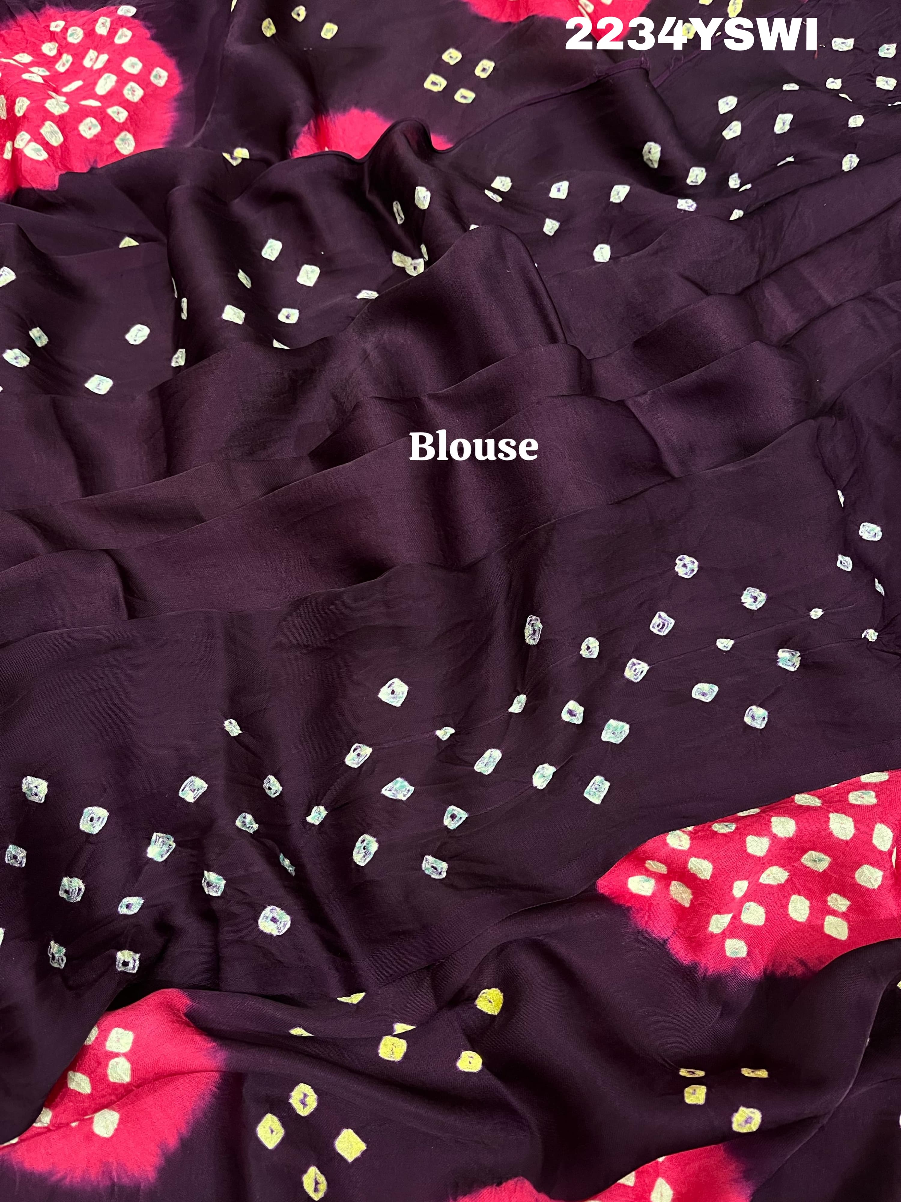 A purple and pink bandhani style saree with detailed patterns and a golden border.