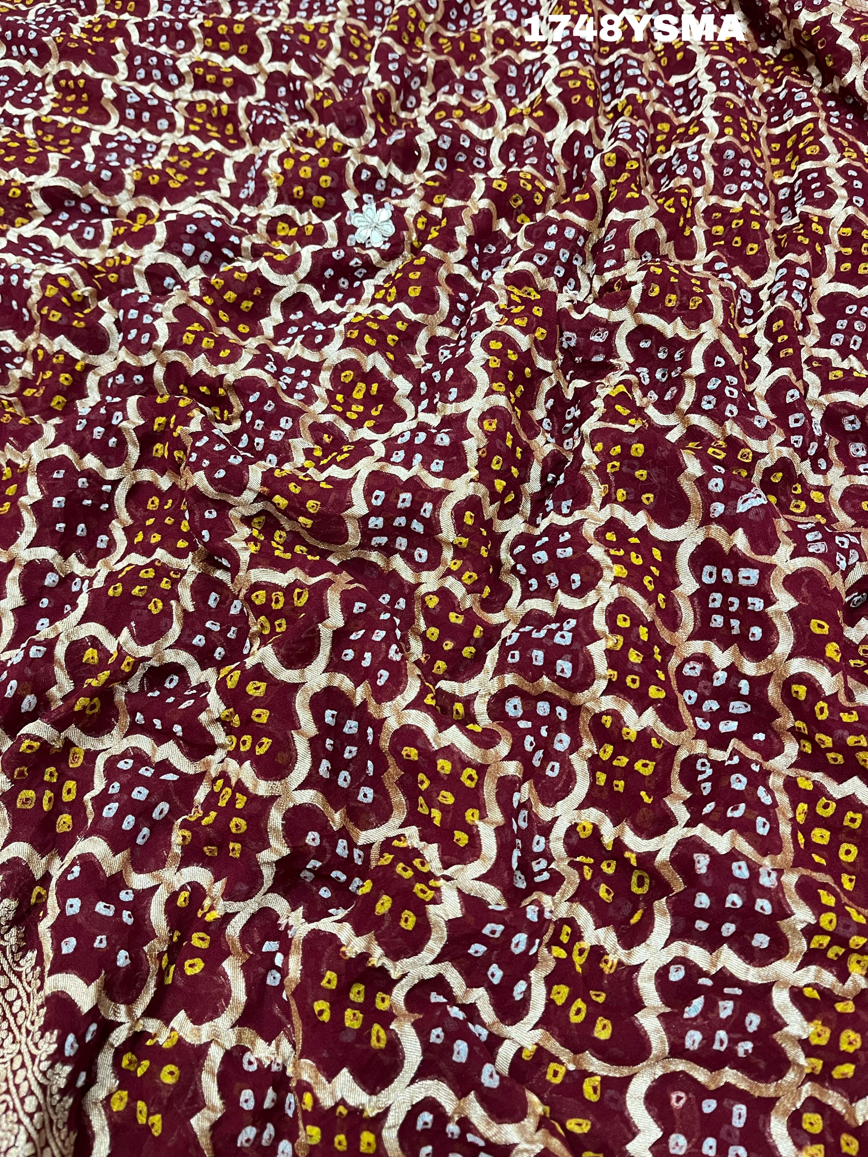 A maroon and gold saree with intricate geometric bandhej patterns and gotapatti handwork.