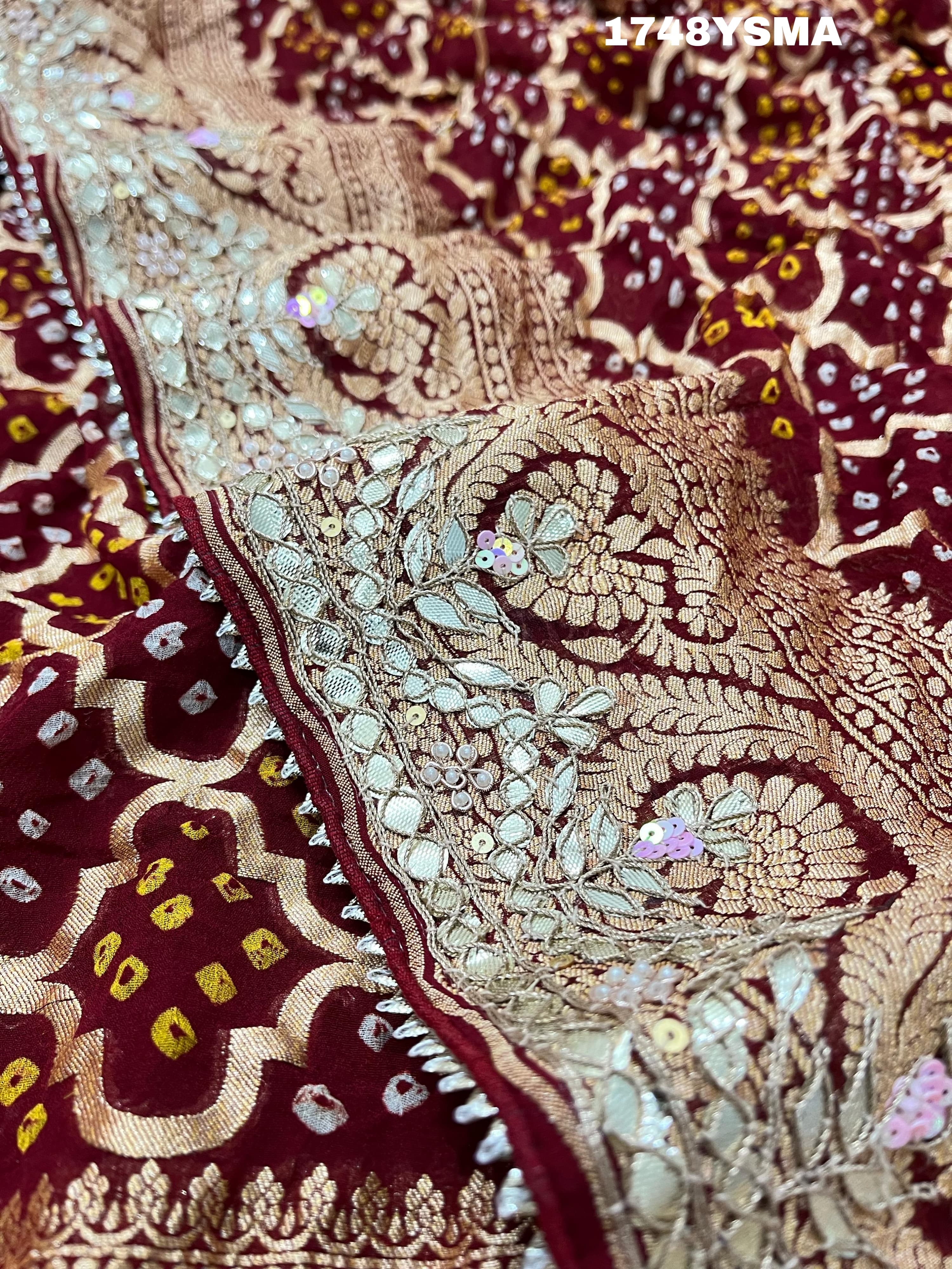 A maroon and gold saree with intricate geometric bandhej patterns and gotapatti handwork.