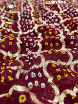 A maroon and gold saree with intricate geometric bandhej patterns and gotapatti handwork.