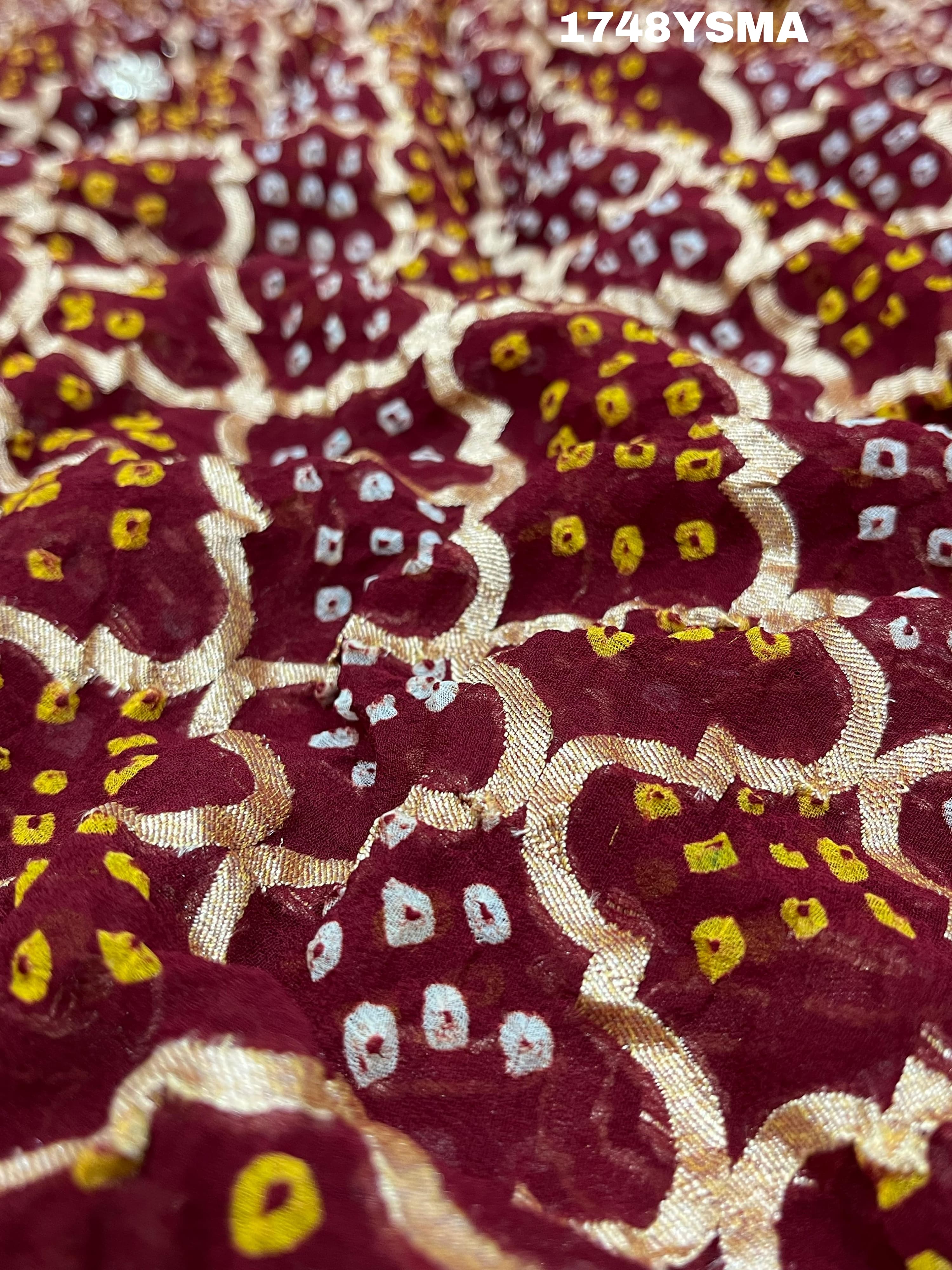 A maroon and gold saree with intricate geometric bandhej patterns and gotapatti handwork.