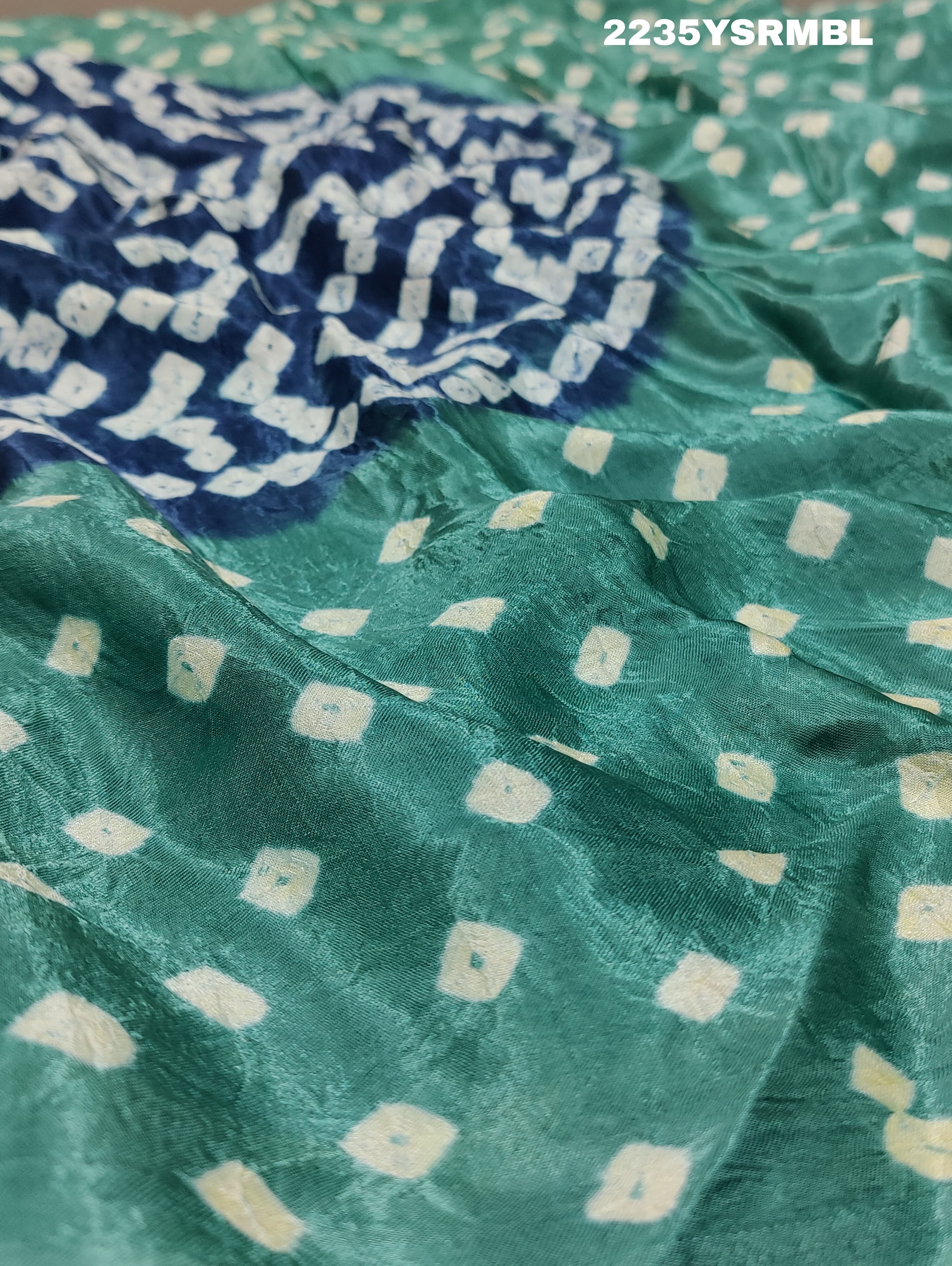 A silk fabric saree with bandhani style patterns in blue and green colors