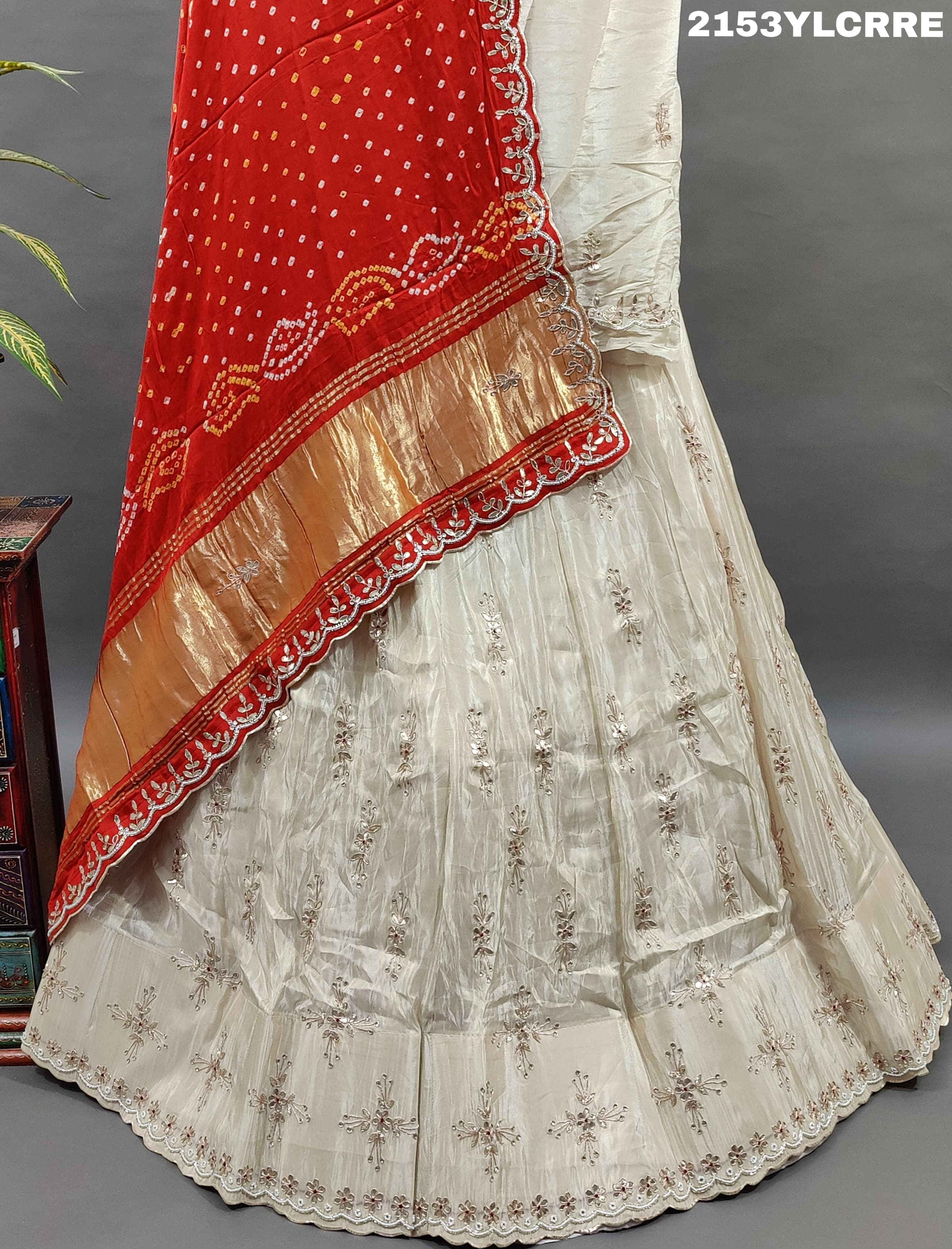 A traditional wear lehenga with bandhani style in red and cream colors