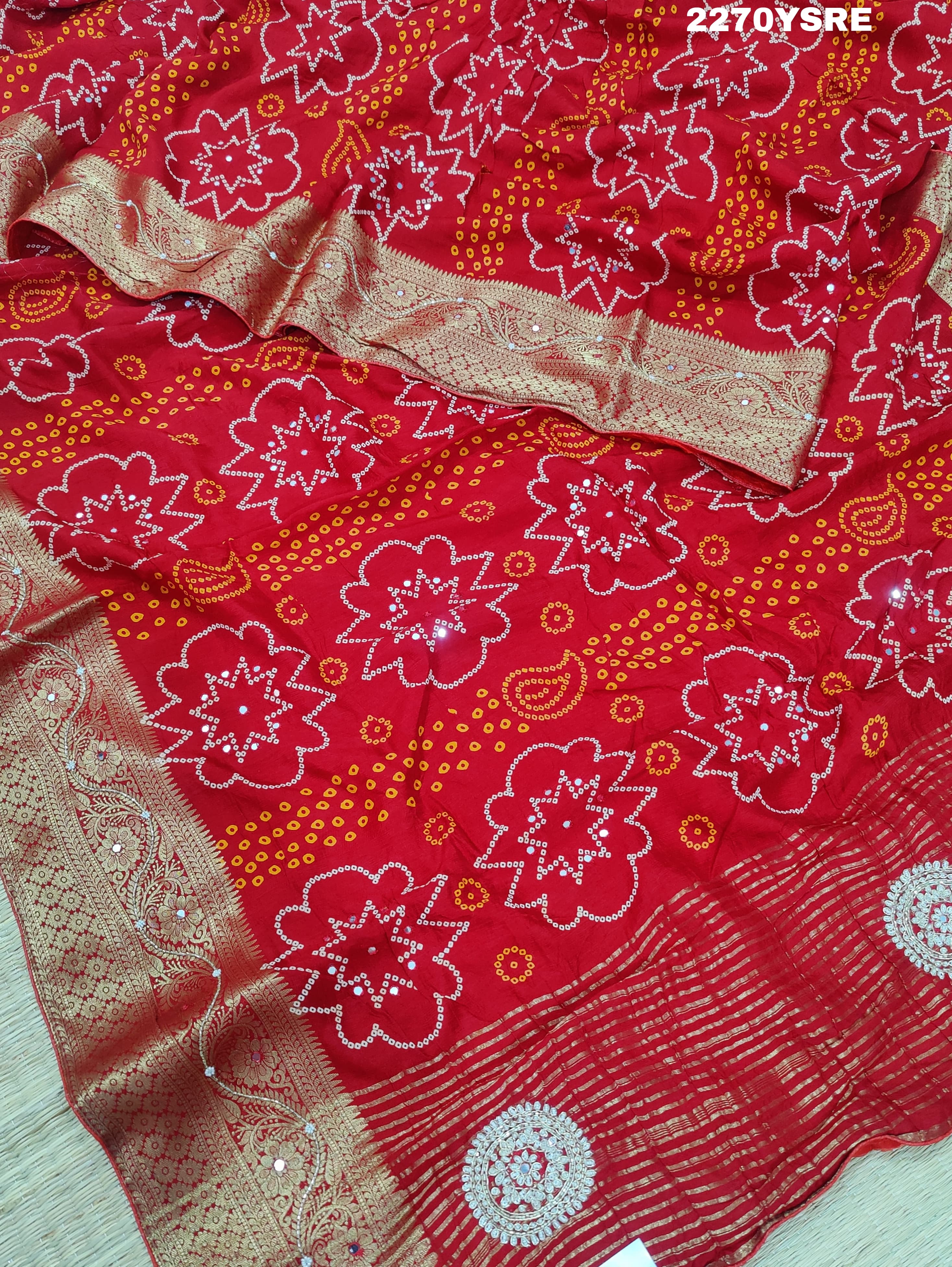 A red and silver bandhani style Dola silk saree with cutdana work and floral patterns, along with a golden border.