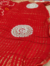 A red and silver bandhani style Dola silk saree with cutdana work and floral patterns, along with a golden border.