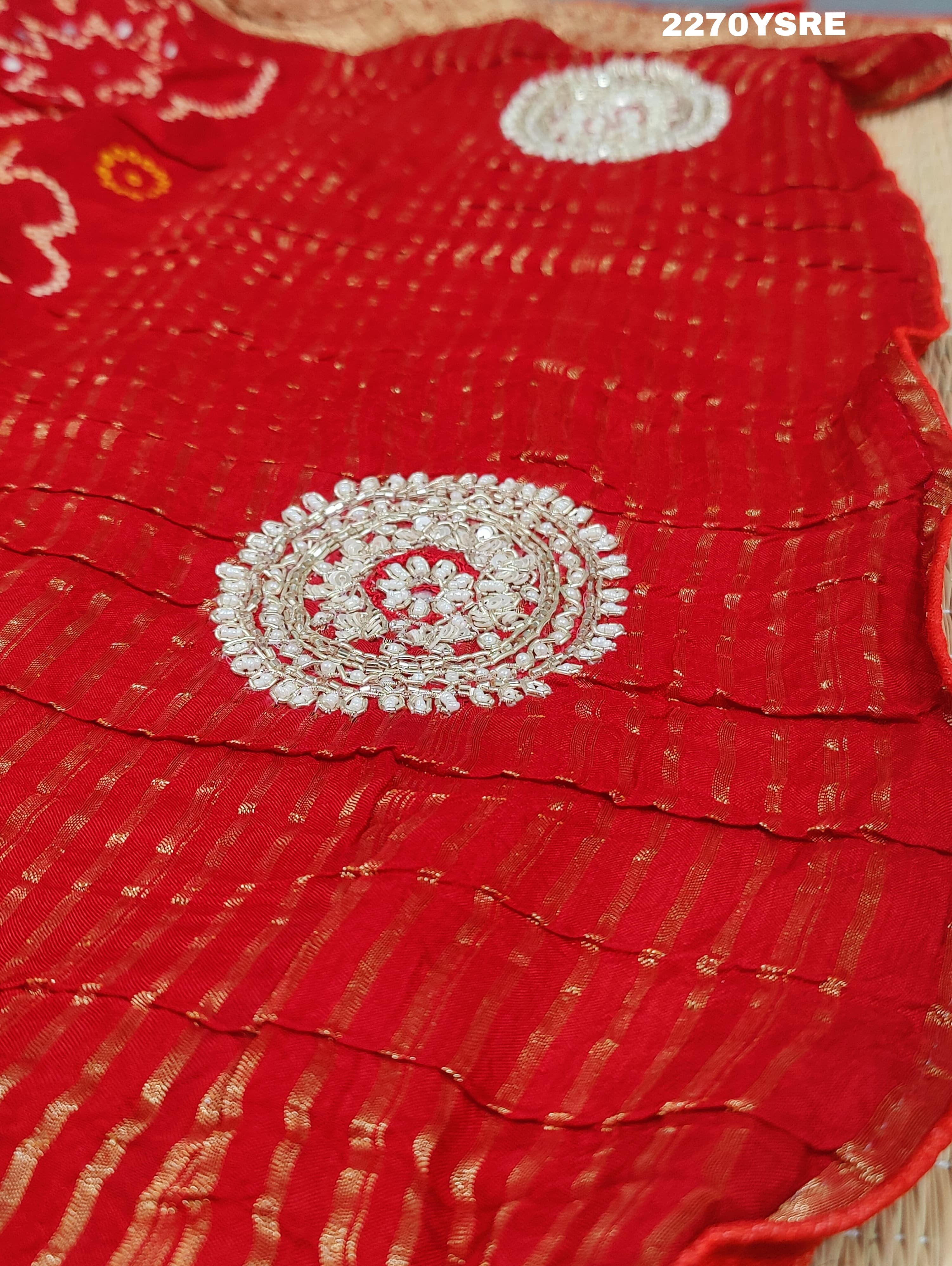 A red and silver bandhani style Dola silk saree with cutdana work and floral patterns, along with a golden border.