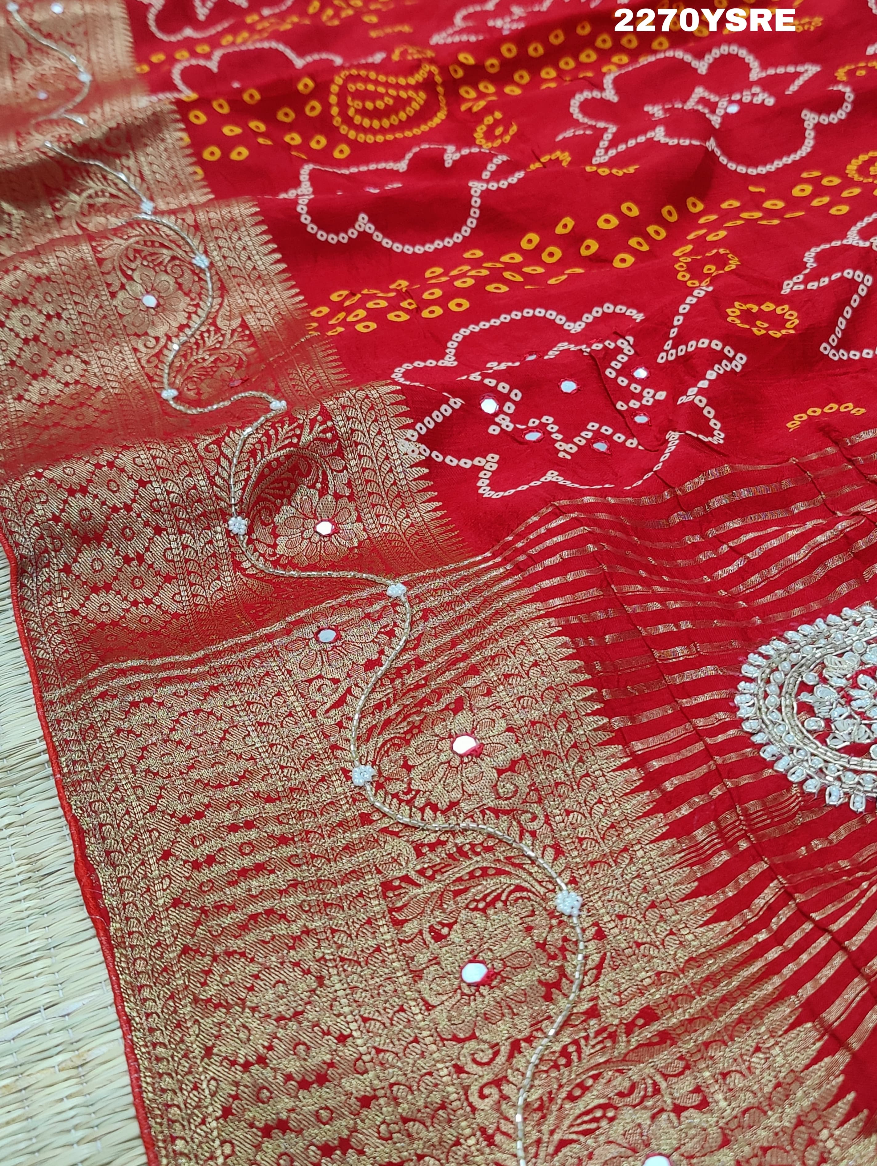 A red and silver bandhani style Dola silk saree with cutdana work and floral patterns, along with a golden border.