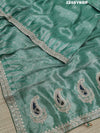 A green Banarsi silk saree with Bollywood style embellishments including sequins and gotapatti work