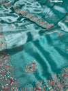 A sea green tissue silk saree with sequence embroidery work in a Bollywood style pattern.