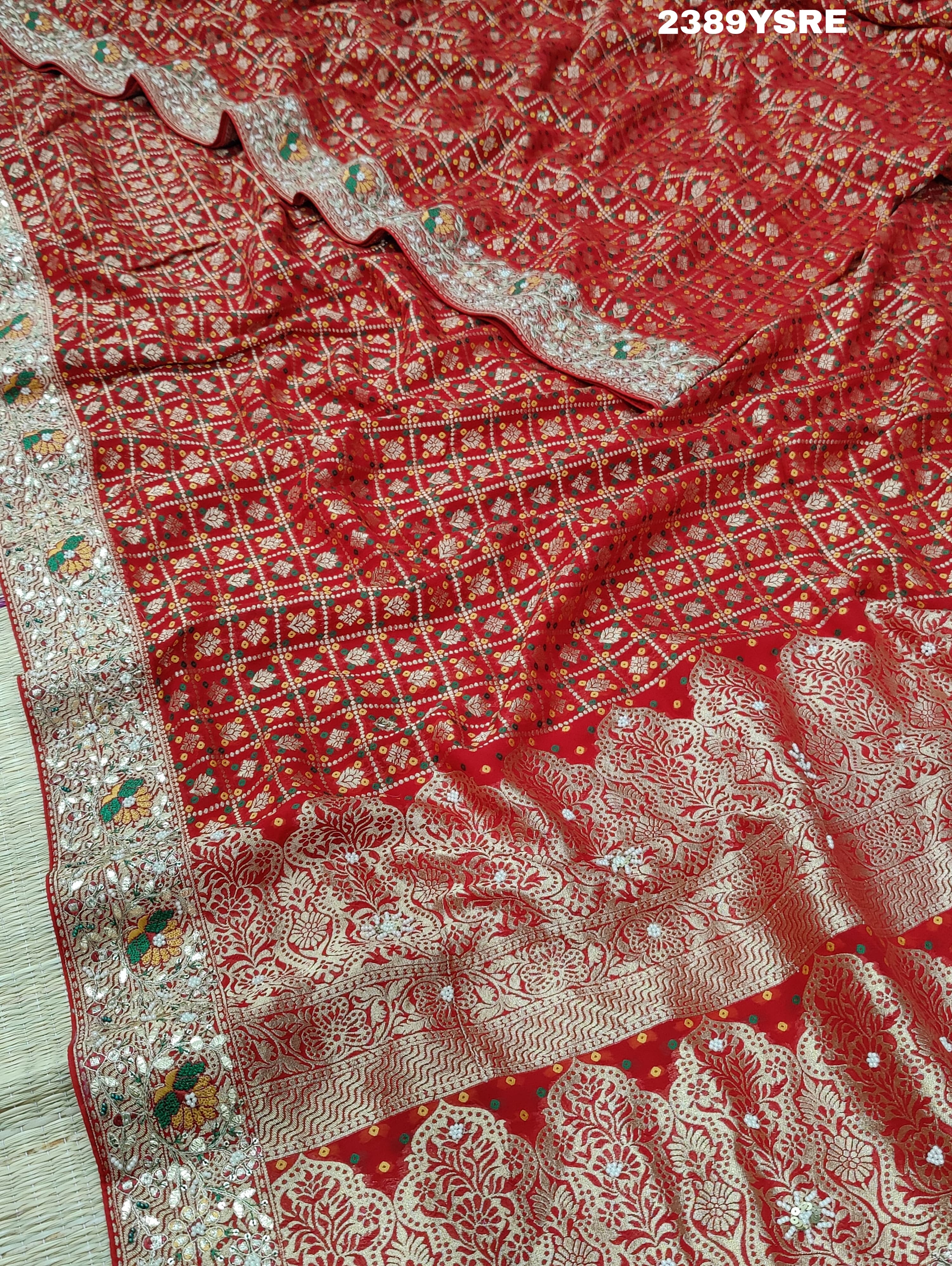 A red Banarasi style saree with gotapatti work, showcasing the detailed embroidery and pattern.