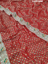 A red Banarasi style saree with gotapatti work, showcasing the detailed embroidery and pattern.