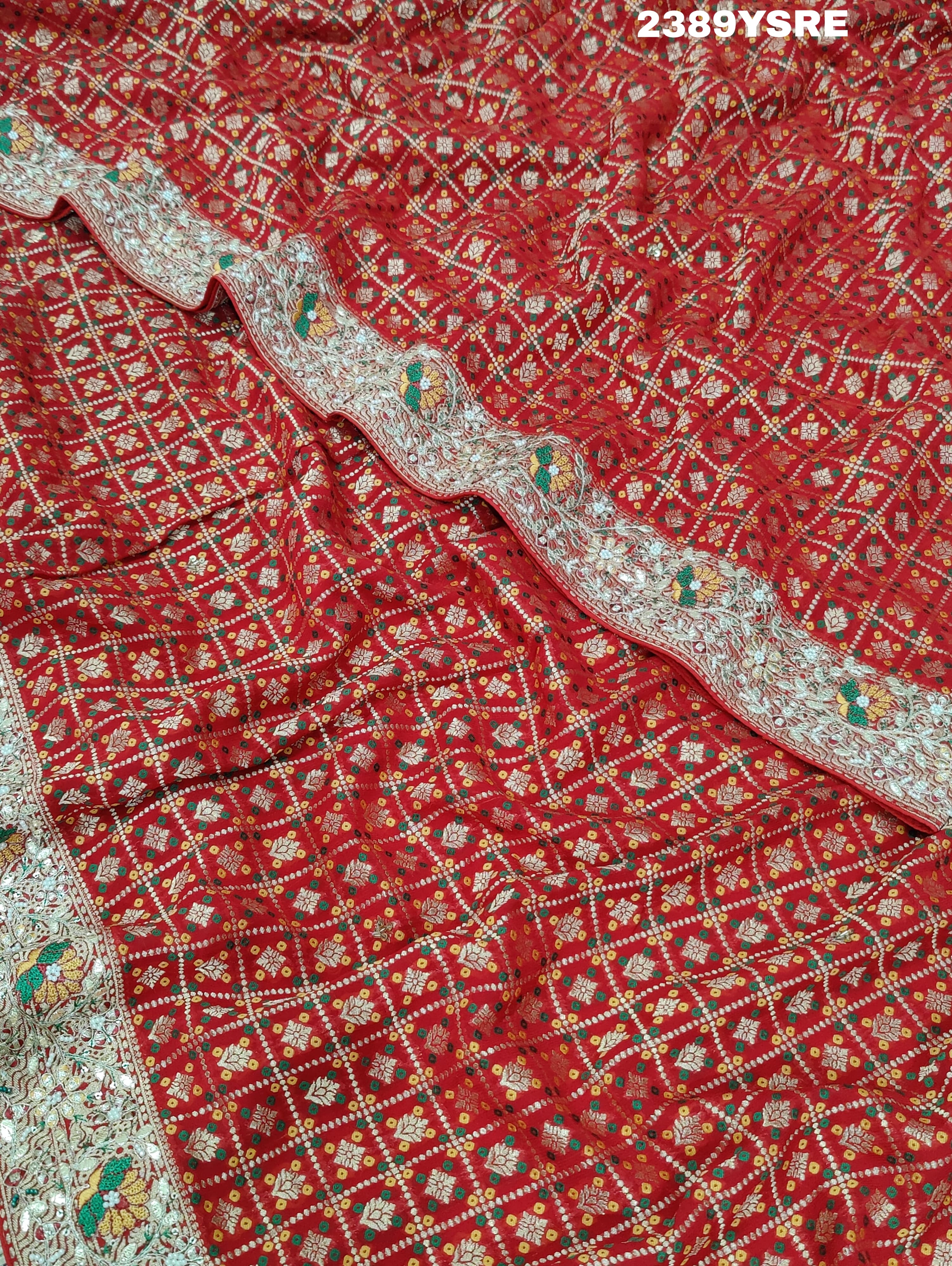 A red Banarasi style saree with gotapatti work, showcasing the detailed embroidery and pattern.