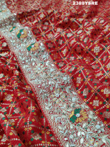 A red Banarasi style saree with gotapatti work, showcasing the detailed embroidery and pattern.