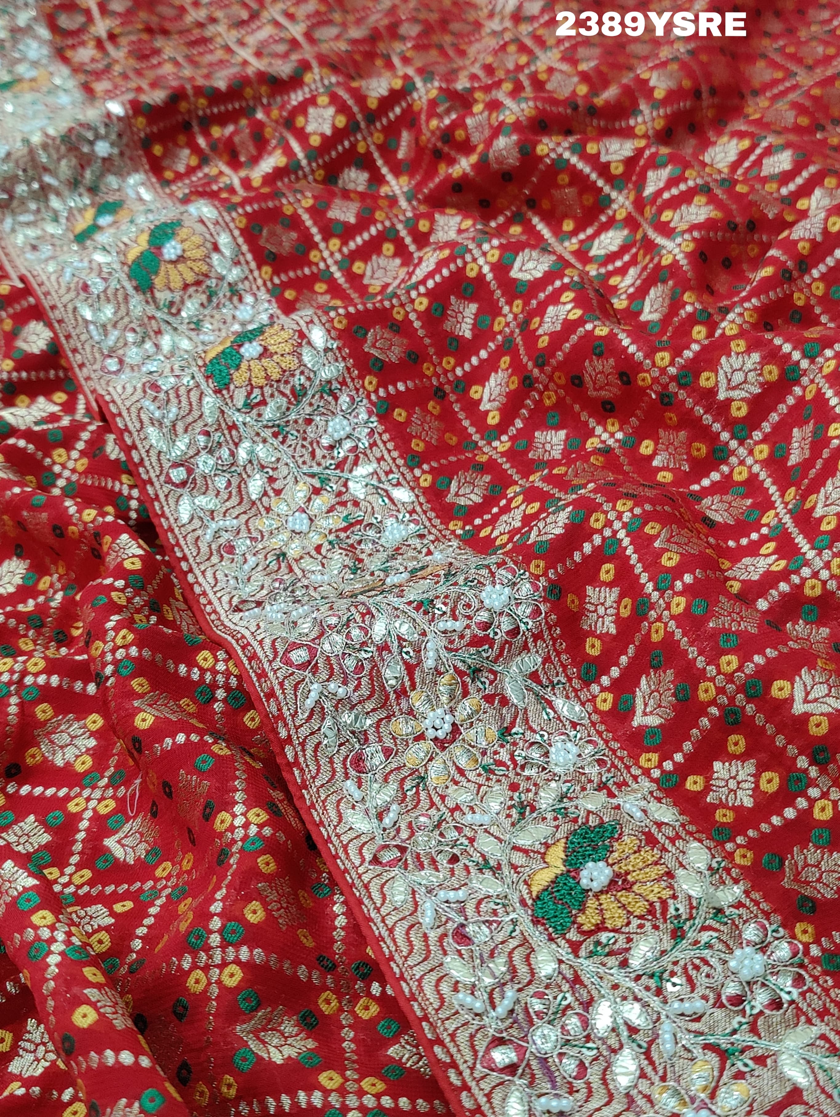 A red Banarasi style saree with gotapatti work, showcasing the detailed embroidery and pattern.