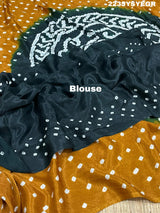 A bandhani style saree with black and yellow patterns on a fabric surface.