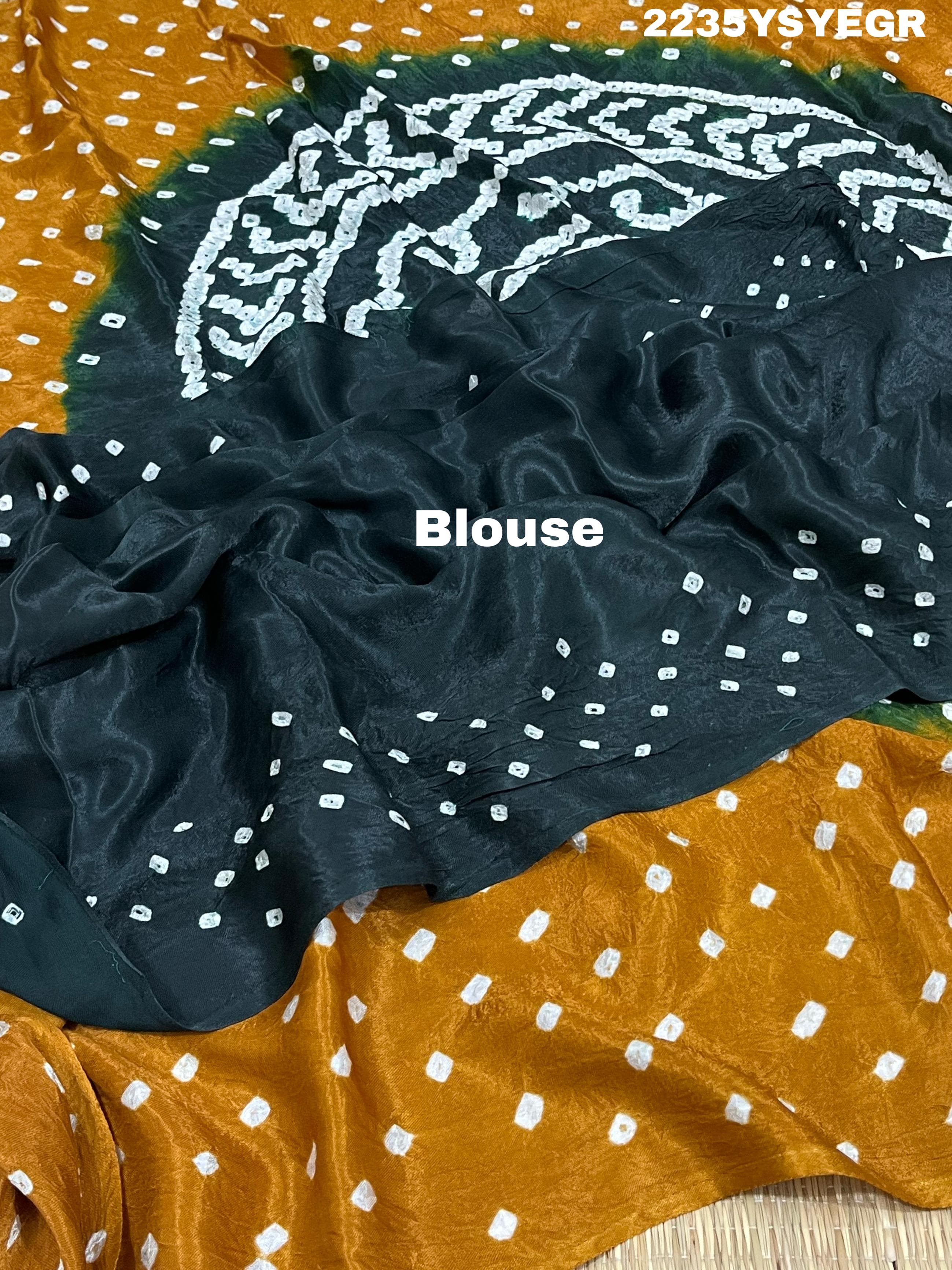 A bandhani style saree with black and yellow patterns on a fabric surface.