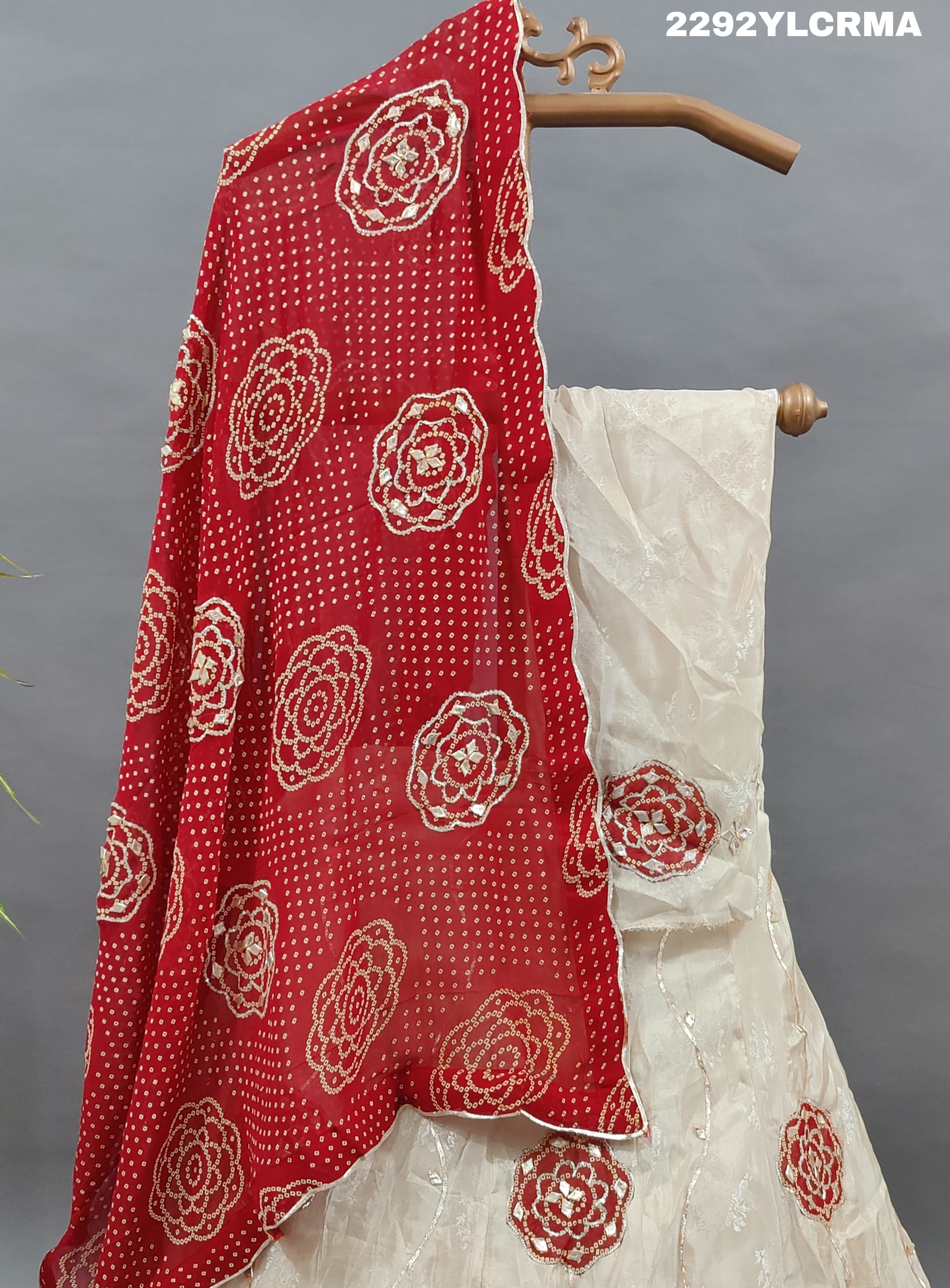 A traditional Indian lehenga with bandhani style patterns in cream and maroon colors