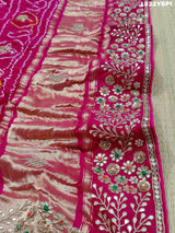 A pink saree with bandhani and gotapatti work, including intricate patterns and embellishments.