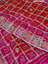 A pink saree with bandhani and gotapatti work, including intricate patterns and embellishments.
