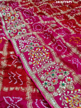 A pink saree with bandhani and gotapatti work, including intricate patterns and embellishments.