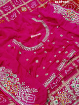 A pink saree with bandhani and gotapatti work, including intricate patterns and embellishments.