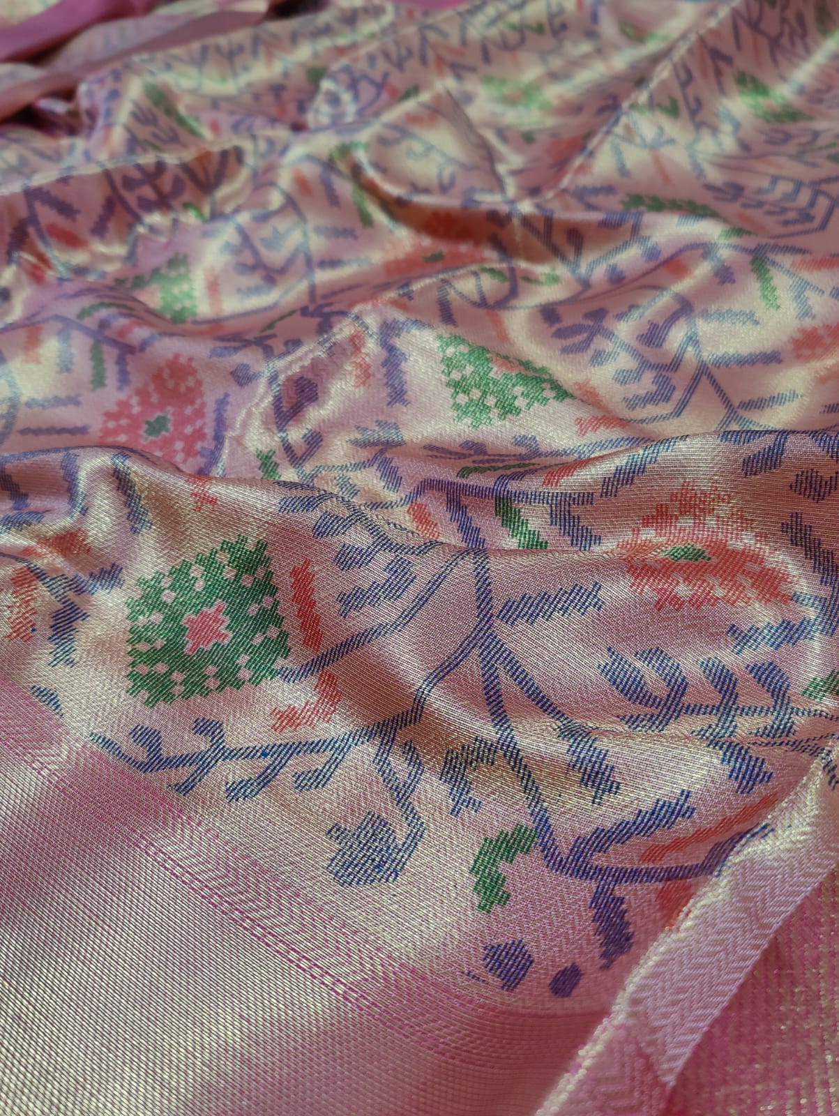 Banarasi silk saree with a printed floral pattern in pink and silver colors, showing detail and texture.