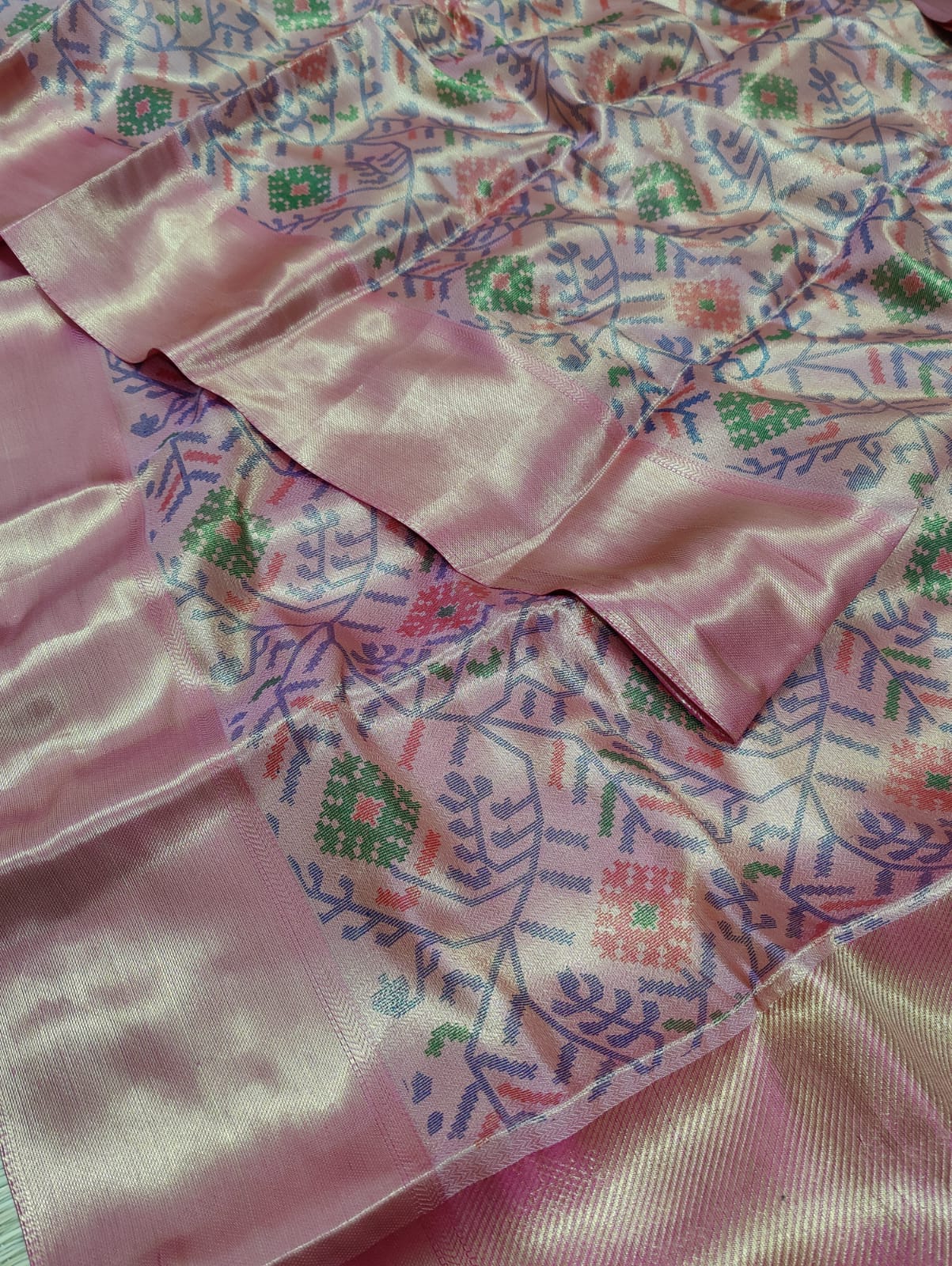 Banarasi silk saree with a printed floral pattern in pink and silver colors, showing detail and texture.