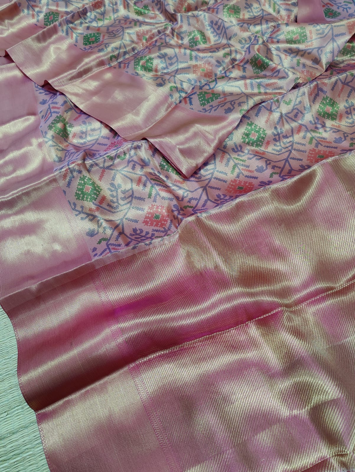 Banarasi silk saree with a printed floral pattern in pink and silver colors, showing detail and texture.
