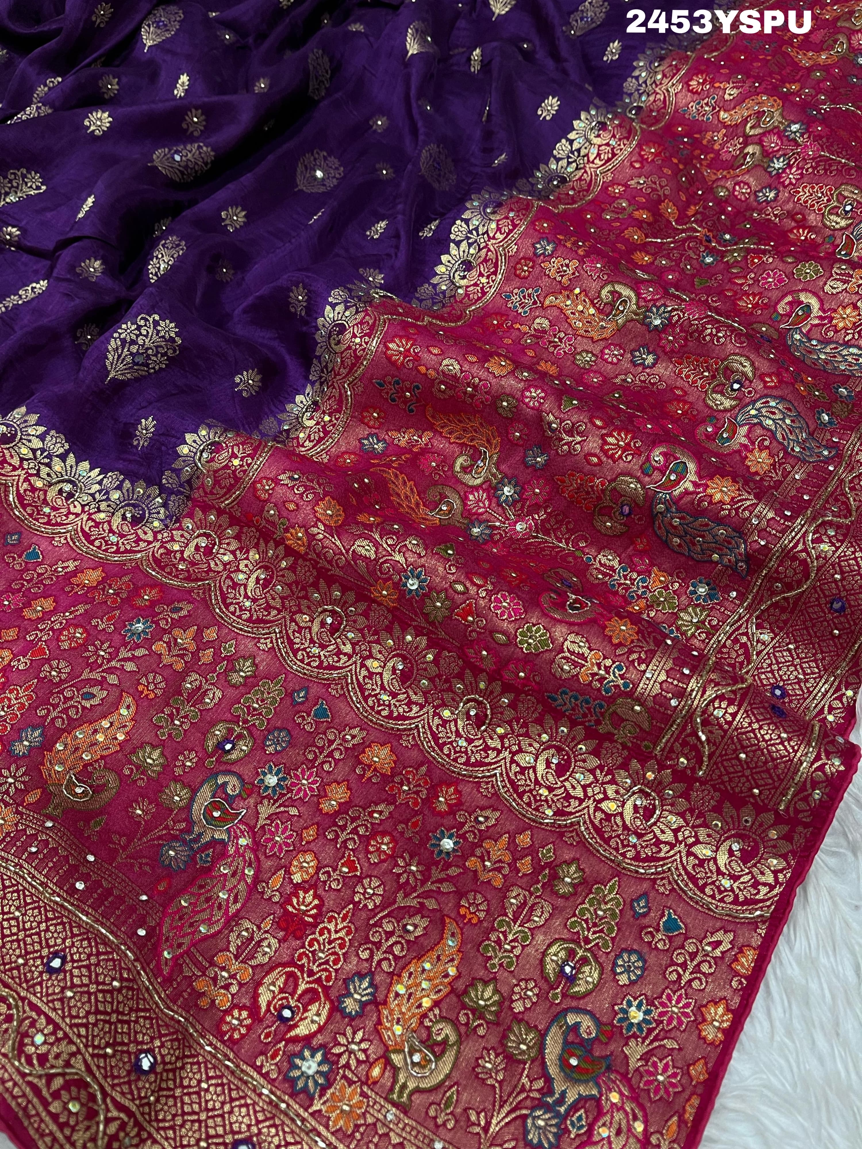 A purple and red Dola silk Banarasi saree with cutdana work, captured with a floral design at the border.