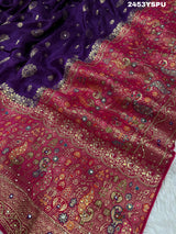 A purple and red Dola silk Banarasi saree with cutdana work, captured with a floral design at the border.