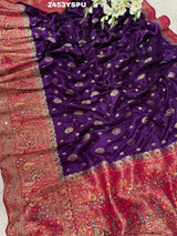 A purple and red Dola silk Banarasi saree with cutdana work, captured with a floral design at the border.