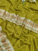 A green Banarasi silk saree with zari weaving and floral embellishments,