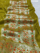 A green Banarasi silk saree with zari weaving and floral embellishments,