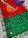 A saree with bandhani style patterns in red and green colors, featuring detailed gotapatti work.