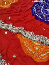 A saree with bandhani style patterns in red and green colors, featuring detailed gotapatti work.