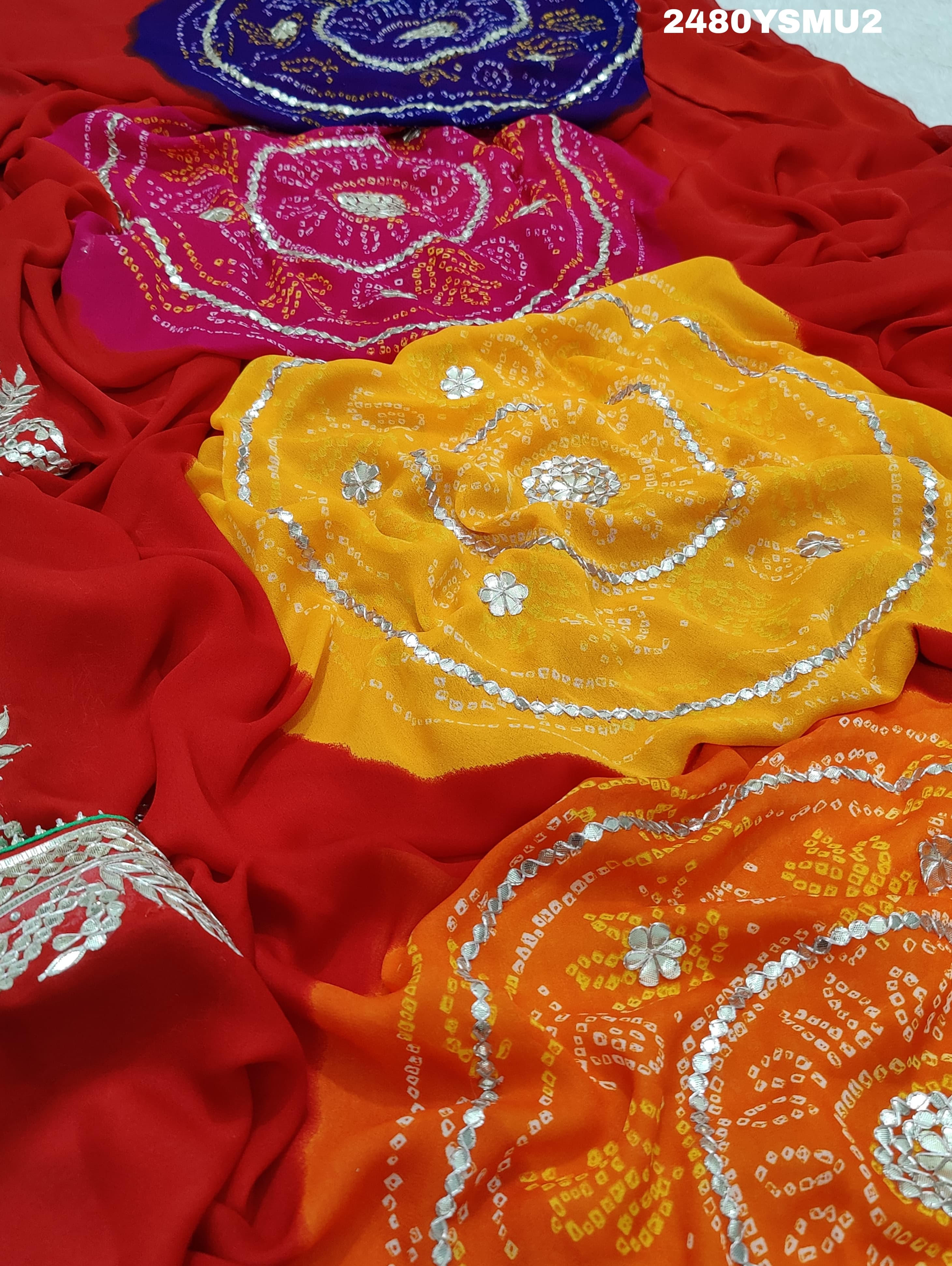 A saree with bandhani style patterns in red and green colors, featuring detailed gotapatti work.