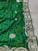 A saree with bandhani style patterns in red and green colors, featuring detailed gotapatti work.