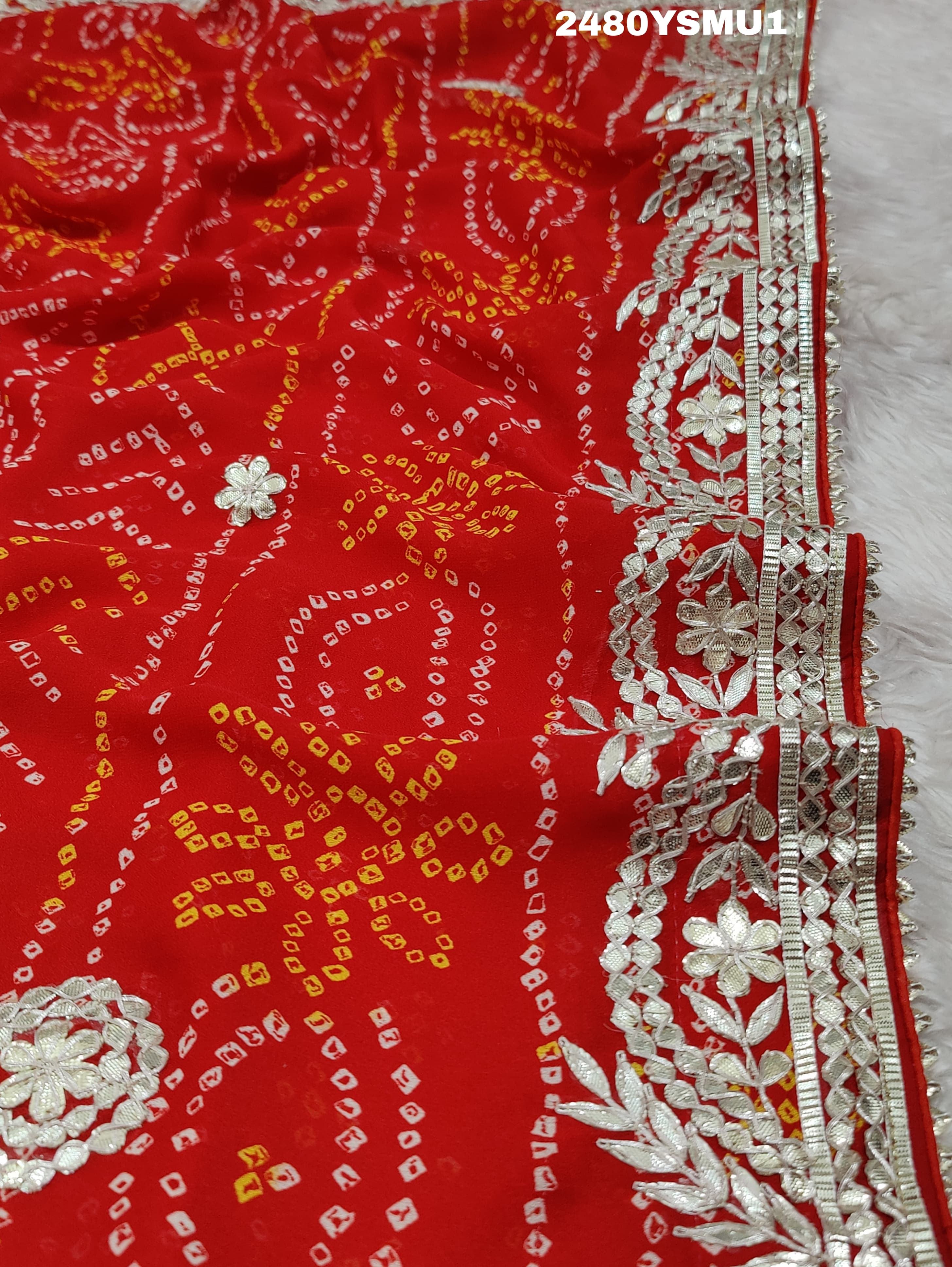 A saree with bandhani style patterns in orange and red colors, featuring detailed gotapatti work.