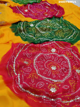 A saree with bandhani style patterns in orange and red colors, featuring detailed gotapatti work.