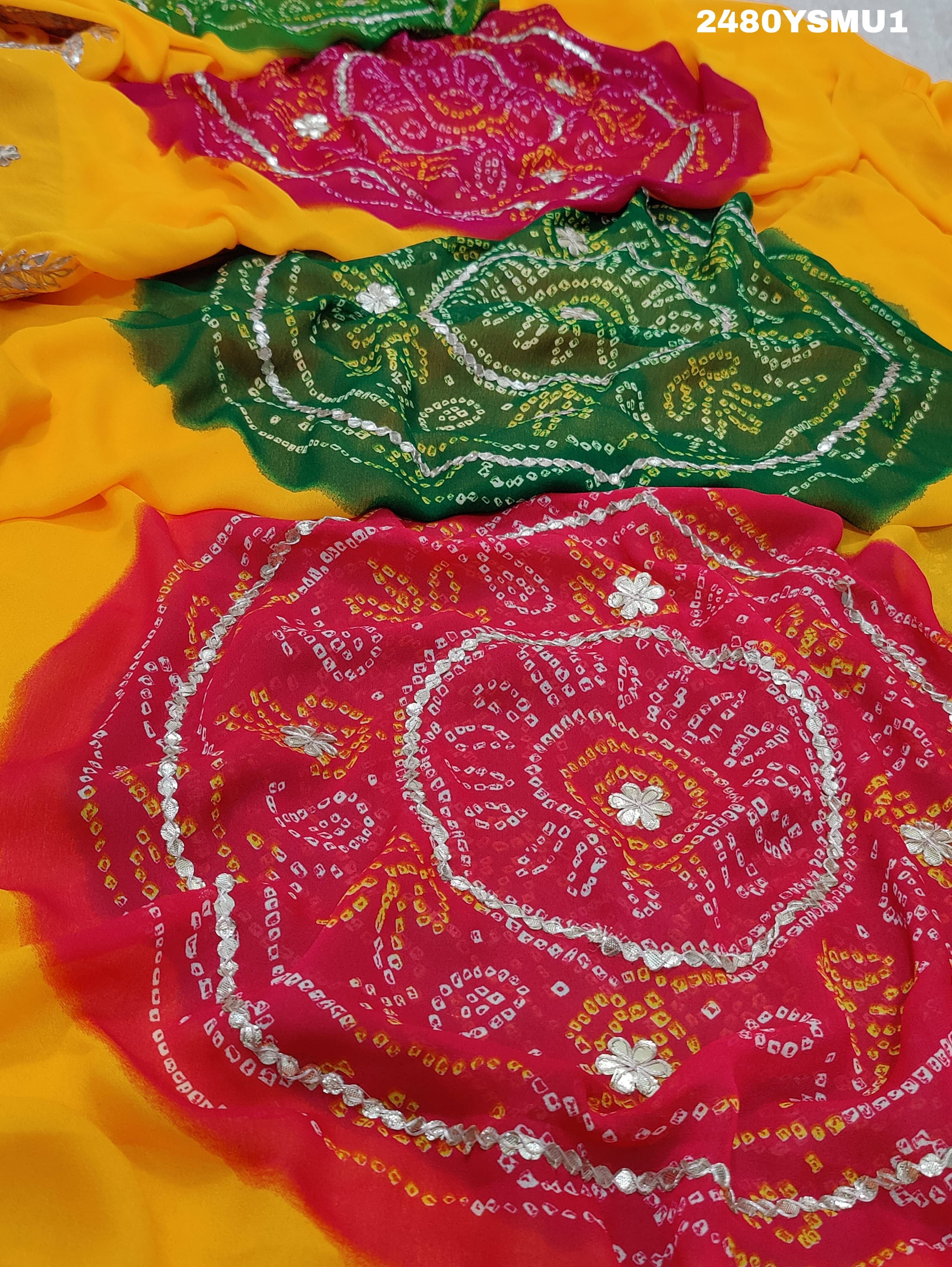 A saree with bandhani style patterns in orange and red colors, featuring detailed gotapatti work.