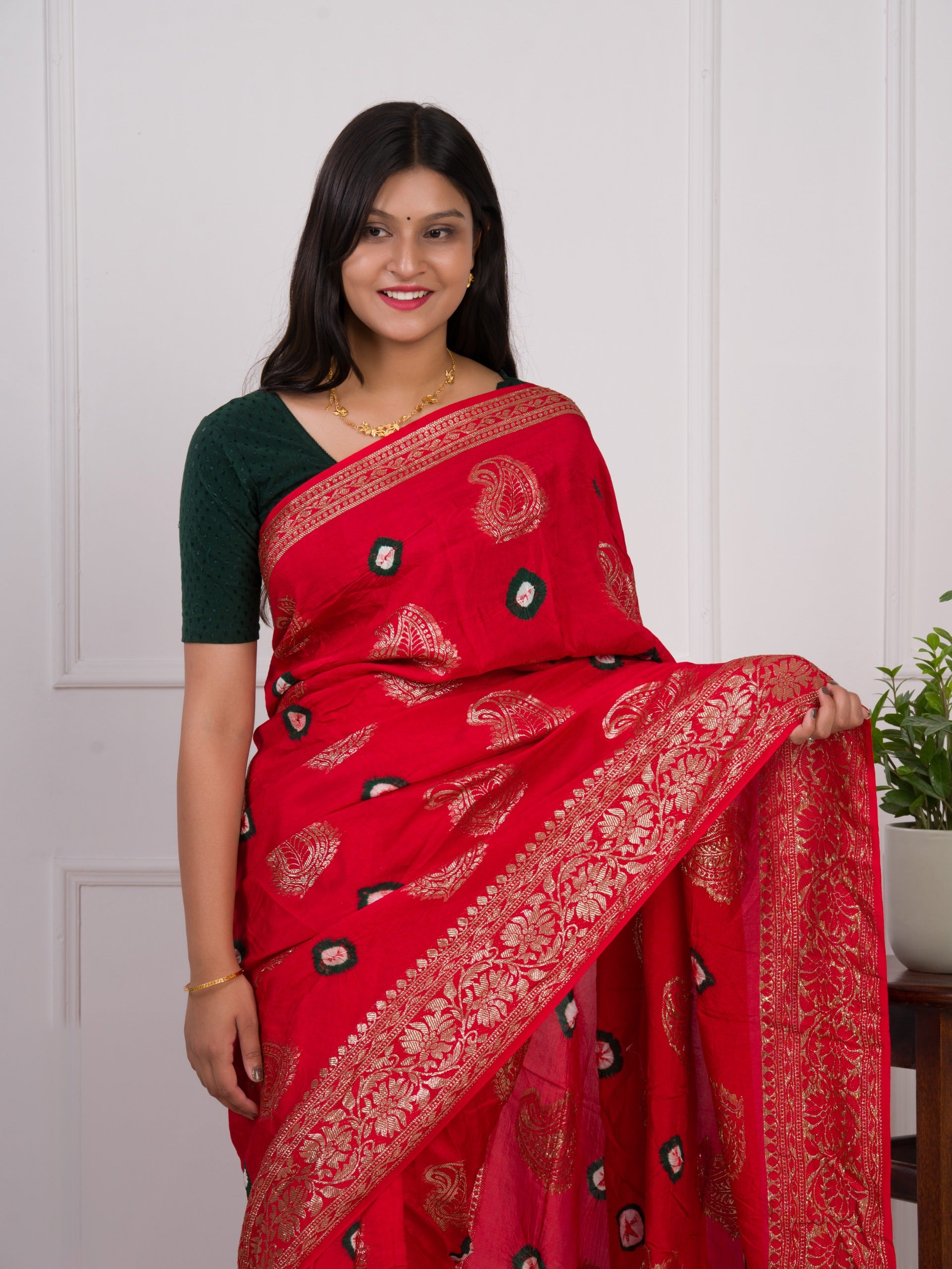 A red saree with green patterns withDola Silk Bandhani Zari Weaving Work