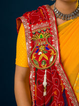 A woman wearing a traditional red and multicolored georgette broach stole with floral patterns and heavy border embellishments.