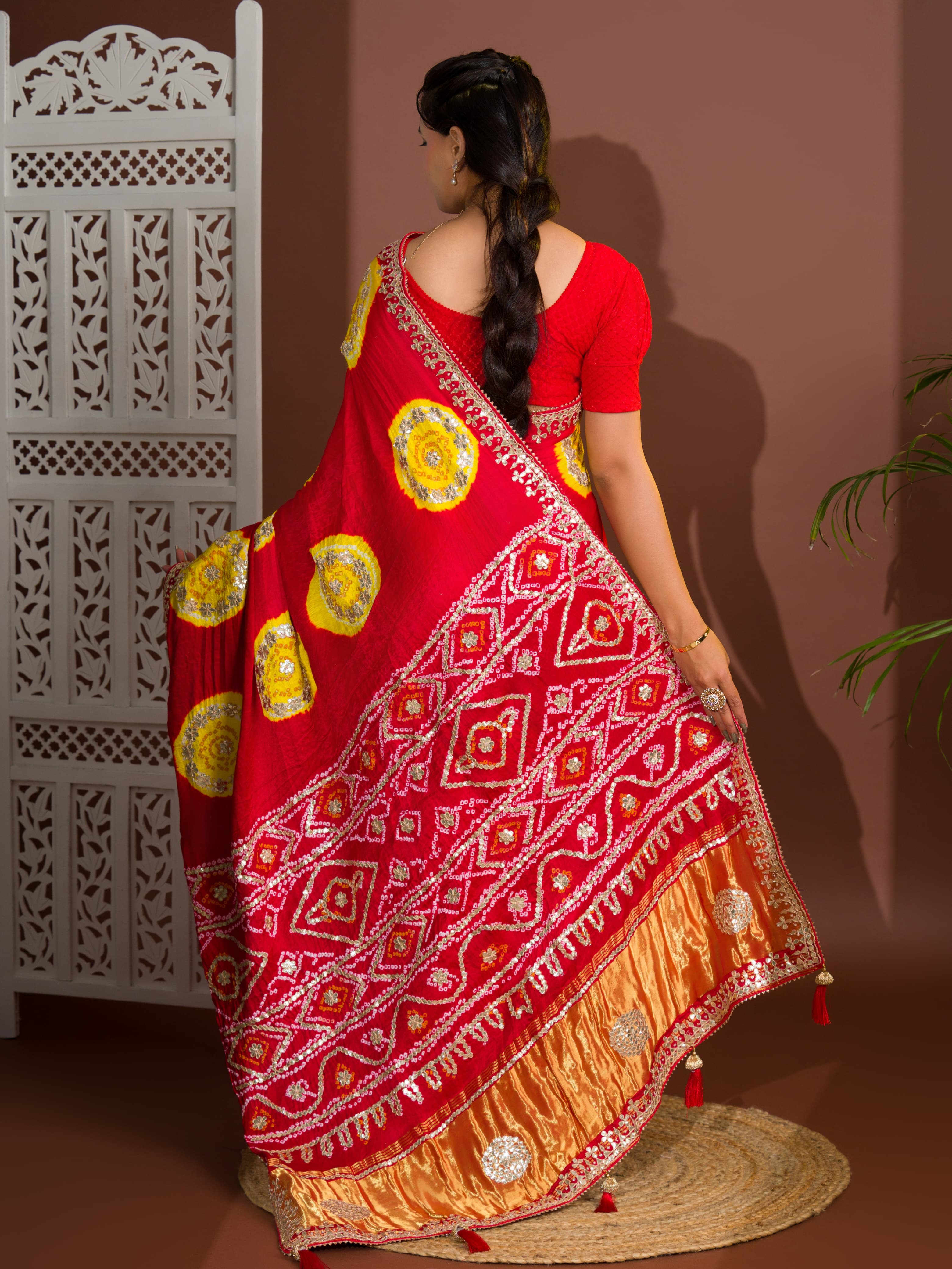 A red saree with bandhej style and gotapatti work in red and yellow colour