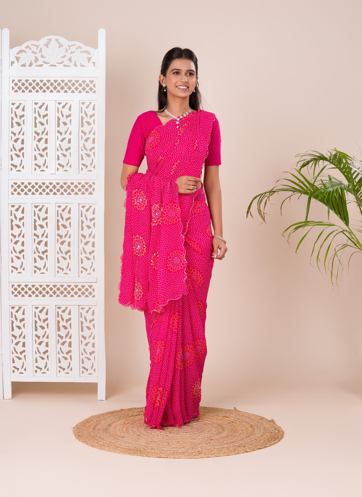 A pink saree with bandhani pattern and aari tari work