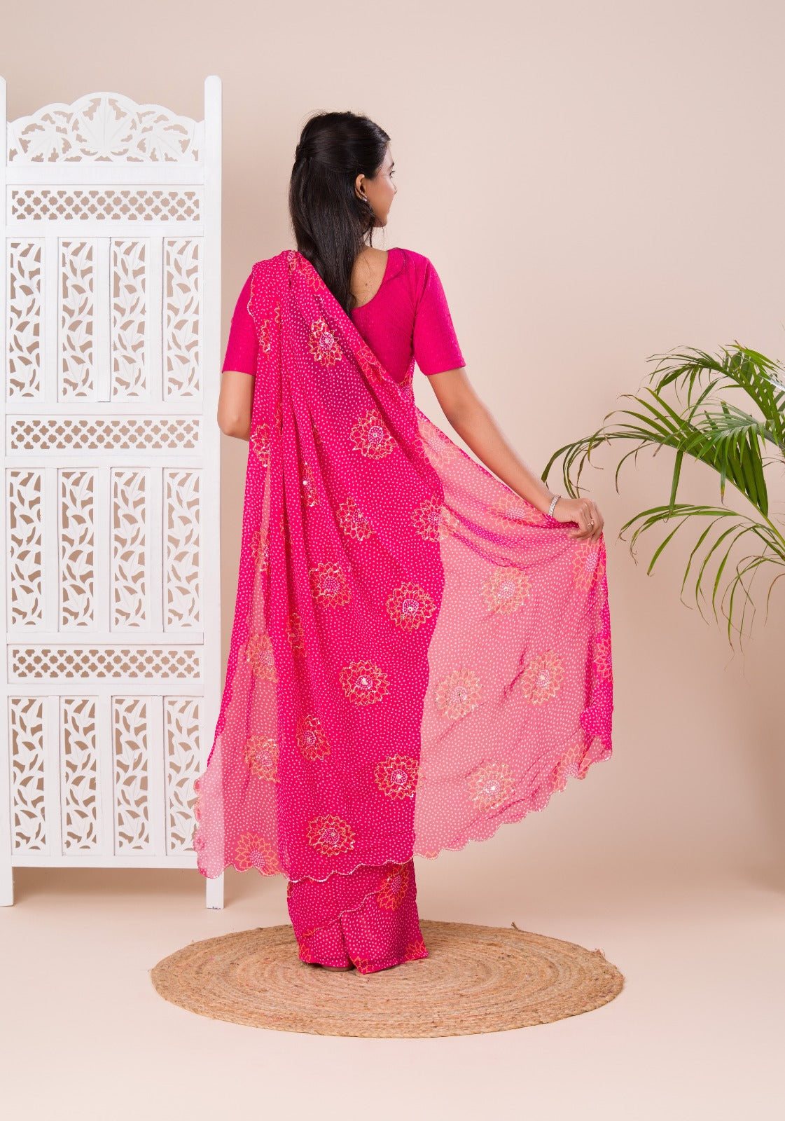 A pink saree with bandhani pattern and aari tari work